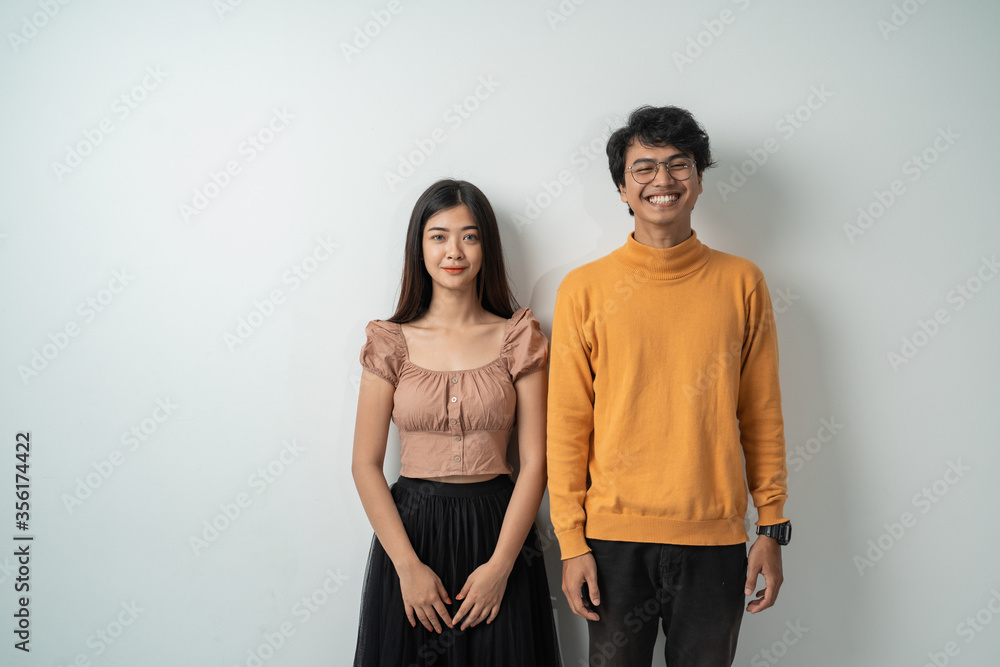 young asian couple smiling while standing against an isolated background young asian couple smiling while standing against an isolated background