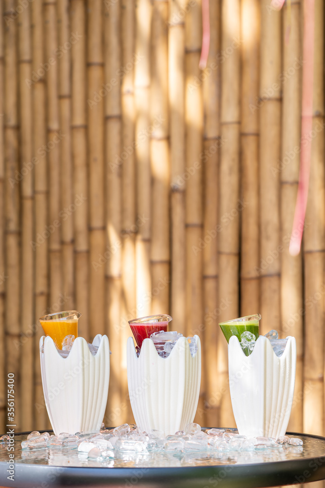 Multiple and mixed herb with fruit juice to red green and orange colour drink in little glass jar that was decorated with ice around.