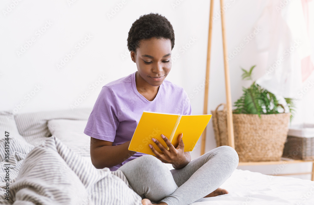 Work with notes. Woman reading notepad, sitting on bed in bedroom interior Work with notes. Woman reading notepad, sitting on bed in bedroom interior