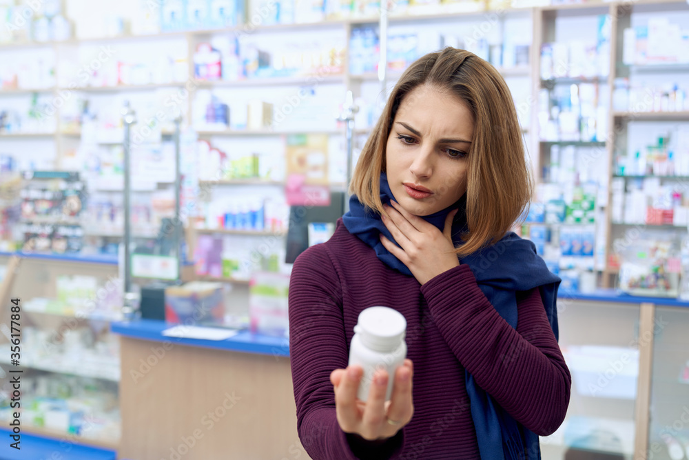 Sick woman reading instruction on pills in drugstore. Sick woman reading instruction on pills in drugstore.