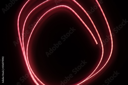 Abstract pink light painting photography, long exposure shot of pink spiral labyrinth maze against a black background. Neon light painting.