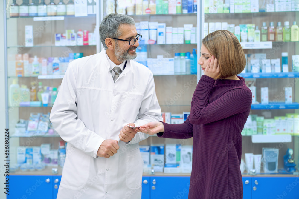 Pharmacist gicing woman with headache pills.