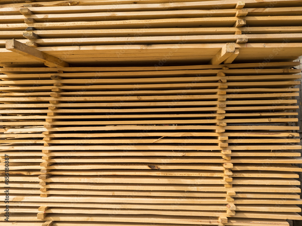 A large pile of boards sawn from trees on a sawmill for the procurement of building materials for construction. Construction industry. A large pile of boards sawn from trees on a sawmill for the procurement of building materials for construction. Construction industry.