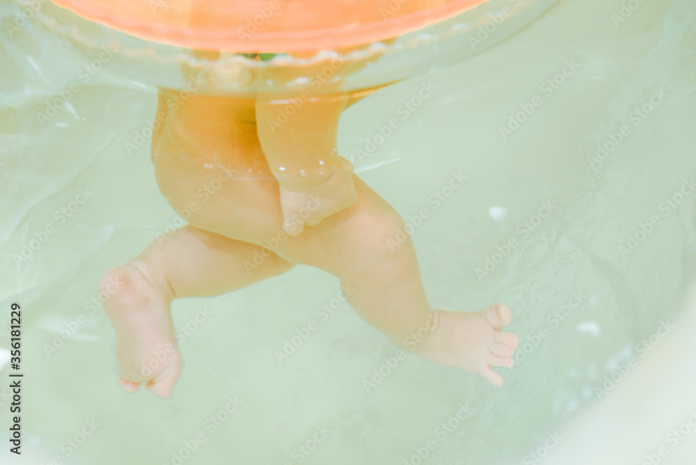 Fototapeta premium Newborn baby swimming in the swimming pool with the swim ring on neck