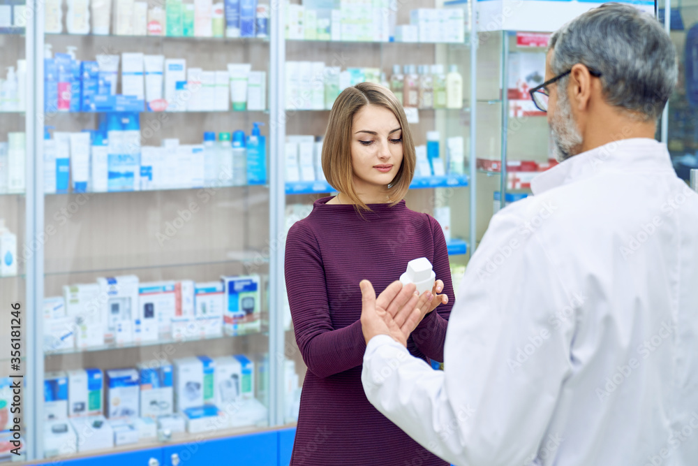 Female customer and pharmacist choosing medicine.