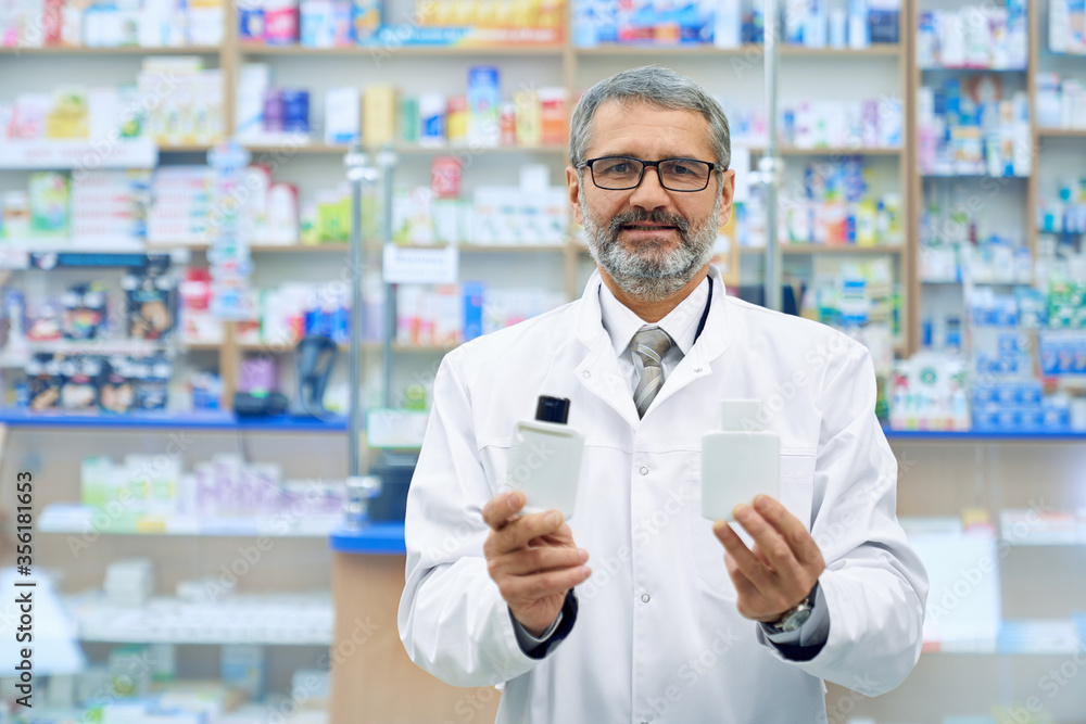 Male pharmacist showing two products in drugstore.