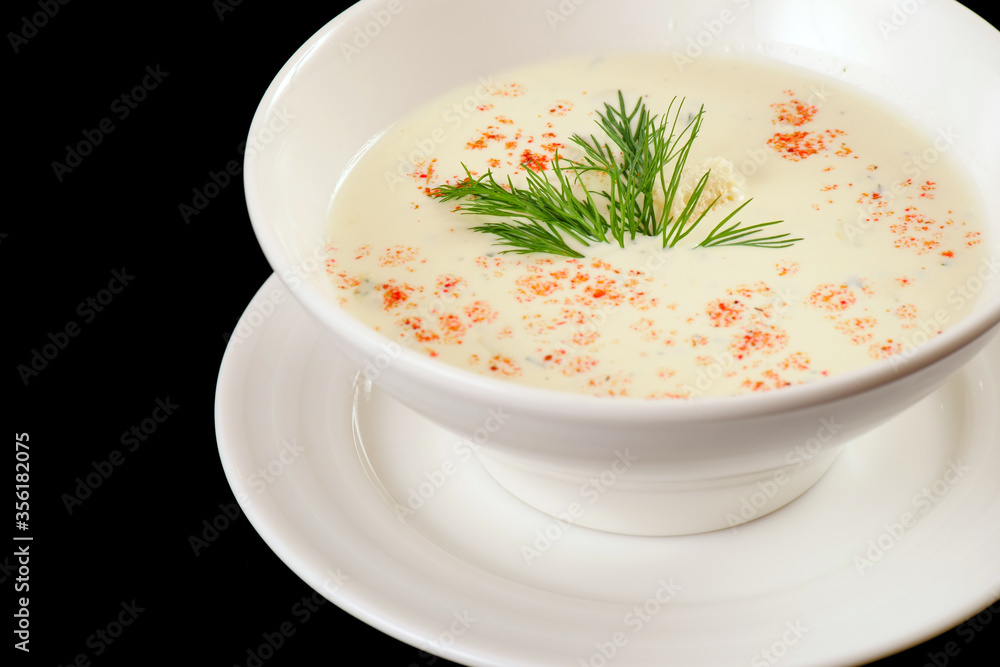 Cauliflower soup. White cream soup with croutons, paprika, dill.Black background