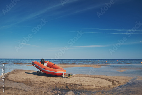 Red rescue boat on the sandy shore of the Baltic Sea.