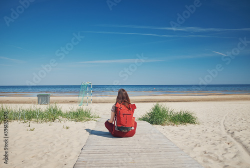 Fototapeta Naklejka Na Ścianę i Meble -  Girl with a backpack on the empty sandy beach of the Baltic Sea.