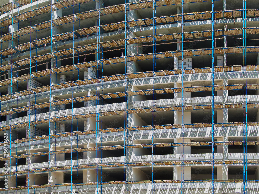 A lot of scaffolding on the facade of a building under construction. Construction of a monolithic house.