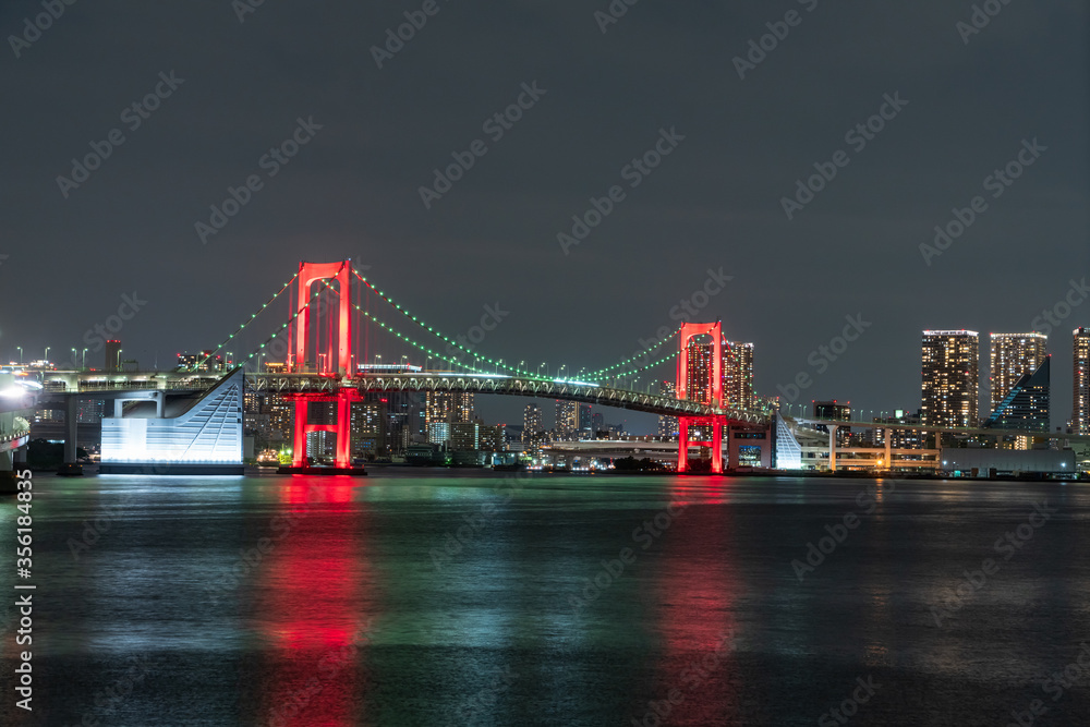 Nightview of Rainbow Bridge, illuminated in red as a sign of coronavirus alert.
