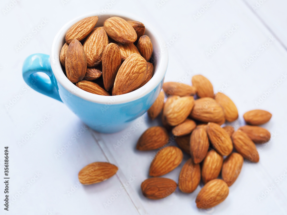 almond seeds in blue cup isolated on white tabel. almond seeds in blue cup isolated on white tabel.