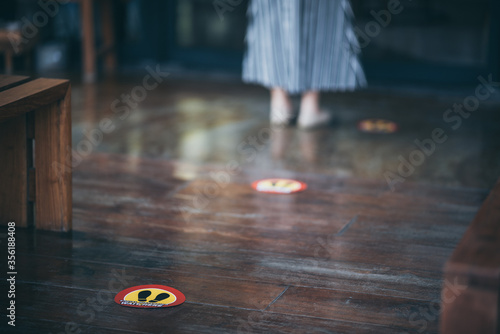 red round sign printed on ground at the font of cafe., People wearing face mask and standing keep distance in line due to coronavirus pandemic safety guideline, COVID-19 social distancing quarantine