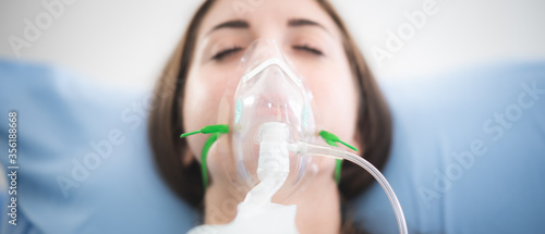 woman patient wearing oxygen mask sleeping on hospital bed, Pre oxygenation for general anesthesia. Surgery equipment photo
