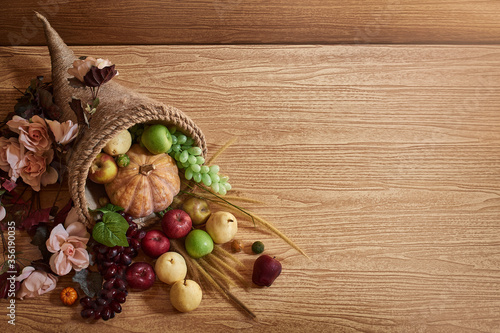 Thanksgiving cornucopia fill in fruit isolated wooden background in autumn and fall harvest season photo