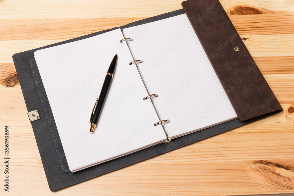 Leather-bound business notebook with a Parker pen on wooden background. Business concept Leather-bound business notebook with a Parker pen on wooden background. Business concept