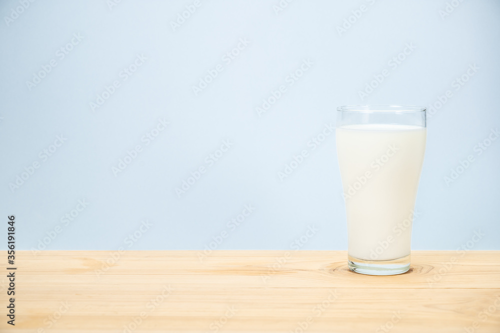 Glass of milk on wooden table and blue background Glass of milk on wooden table and blue background