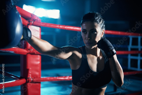 Female fighter training in boxing gloves. © serhiibobyk