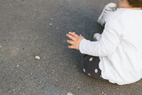 One year old baby sitting on asphalt, looking away from camera. No face visible.
