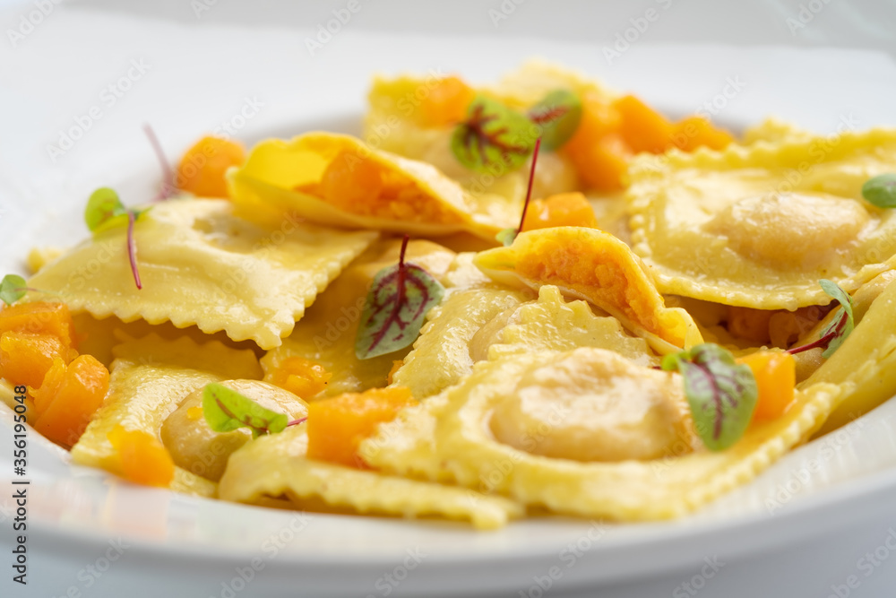 Cooked ravioli with pumpkin and Parmesan on a white plate close up
