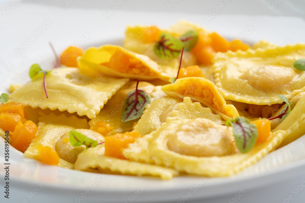 Cooked ravioli with pumpkin and Parmesan on a white plate close up Cooked ravioli with pumpkin and Parmesan on a white plate close up