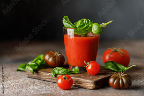 Tomato juice and fresh tomato with basil on rustic background