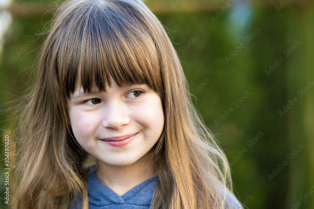 Portrait of pretty child girl with gray eyes and long fair hair smiling outdoors on blurred green bright background. Cute female kid on warm summer day outside. Portrait of pretty child girl with gray eyes and long fair hair smiling outdoors on blurred green bright background. Cute female kid on warm summer day outside.