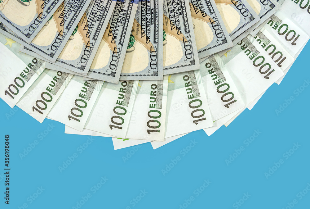 Banknotes of 100 euros and 100 dollars are beautifully laid out on a blue background. Much money. Financial concept. Banknotes of 100 euros and 100 dollars are beautifully laid out on a blue background. Much money. Financial concept.