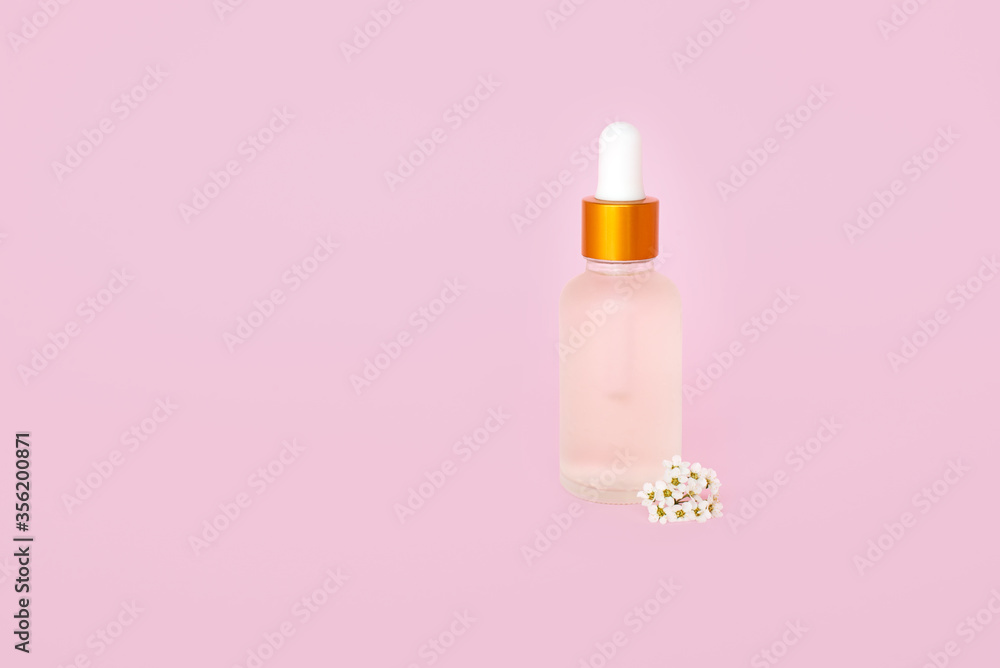 Glass cosmetik bottle with oil. container for a product for women with small white flowers on a turquoise background. Cosmetic jar. Place for text Glass cosmetik bottle with oil. container for a product for women with small white flowers on a turquoise background. Cosmetic jar. Place for text