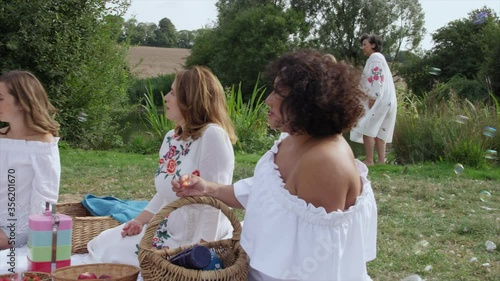 MS PAN Women and girls (6-7) eating strawberries during picnic / Dinton, Wiltshire, United Kingdom