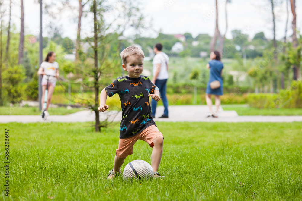 Little boy playing football in park.