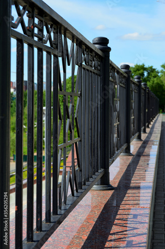 Iron black forged fence along a walkway on the city promenade