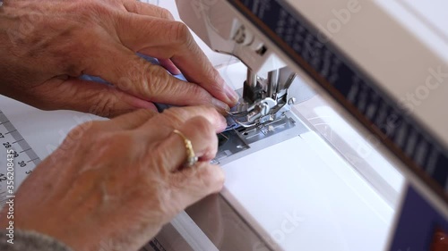 Sewing machine close up stitching a homemade cotton face mask. Woman hands sew a reusable blue facial mask to prevent virus spread.