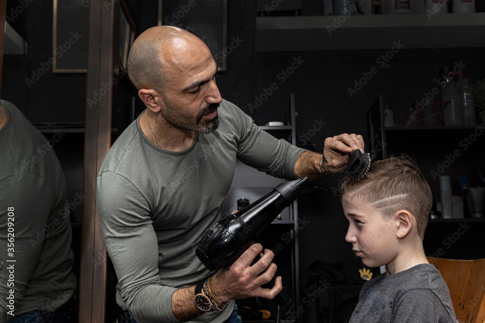 Hairdresser cuts the hair of a boy in a barbershop Hairdresser cuts the hair of a boy in a barbershop