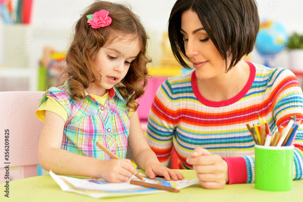 Close up portrait of little cute girl with mother drawing Close up portrait of little cute girl with mother drawing