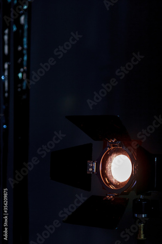 Studio lighting spotlight. Warm stage spotlight shines on dark background. Antique lamp with blinds. Vertical photo with space for your label or logo