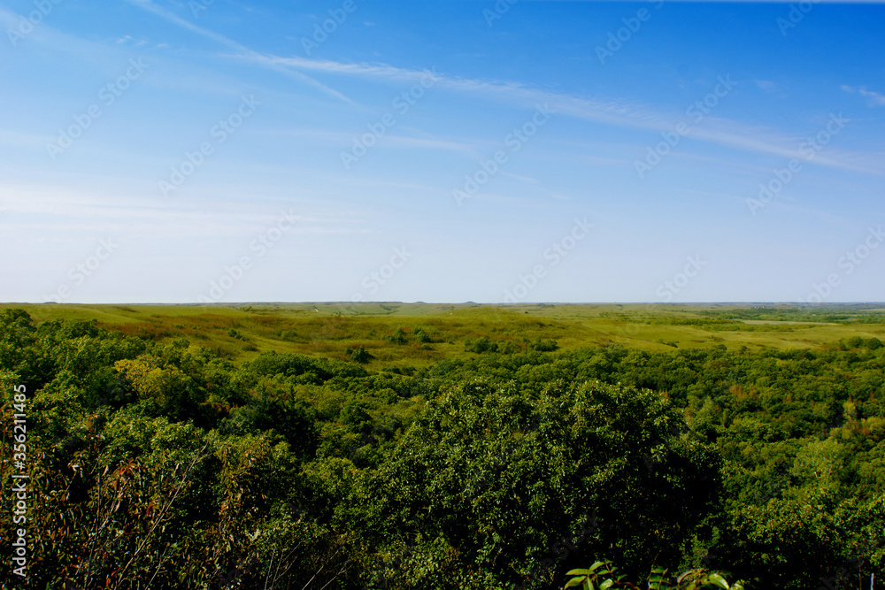 A green field and valley in the Flint Hills of Kansas with blue sky