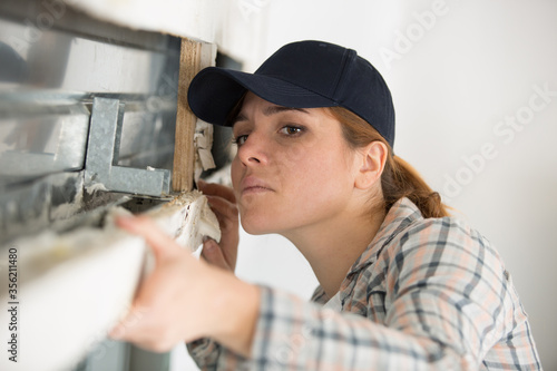 young female builder working with window