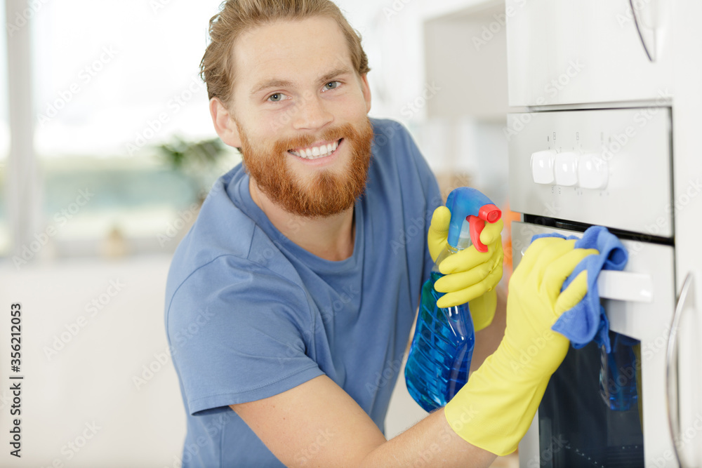 man cleaning domestic oven in kitchen man cleaning domestic oven in kitchen
