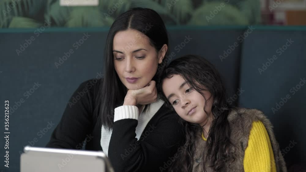 MS Mother and daughter (8-9) sitting and using digital tablet / Norwich, Norfolk, England, UK MS Mother and daughter (8-9) sitting and using digital tablet / Norwich, Norfolk, England, UK