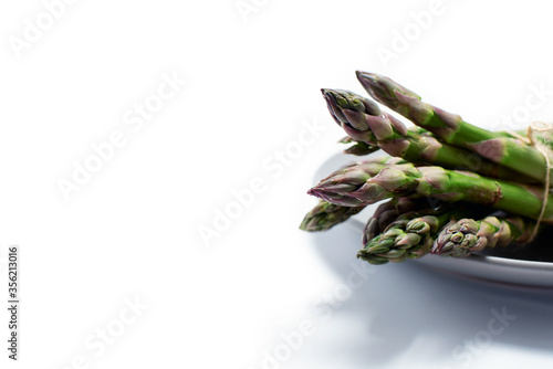Bunch of green asparagus on a plate on a white background