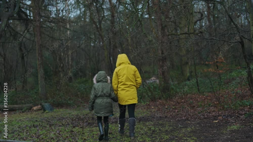 WS Mother and daughter (8-9) walking into forest on rainy day / Norwich, Norfolk, England, UK WS Mother and daughter (8-9) walking into forest on rainy day / Norwich, Norfolk, England, UK