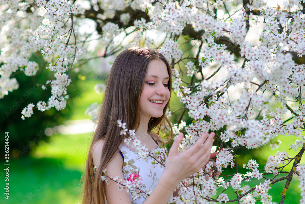 Beautiful young girl in a white dress walks in the park, flowering trees, spring, sunny weather. Blooming garden, beautiful nature, summer. Style, clothes Beautiful young girl in a white dress walks in the park, flowering trees, spring, sunny weather. Blooming garden, beautiful nature, summer. Style, clothes