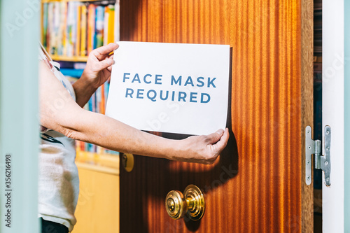 Wallpaper Mural Teacher at an academy putting up a sign on the door requiring the wearing of a medical mask so as not to spread the covid19. Reopening and adaptation of schools to the new normal. Torontodigital.ca
