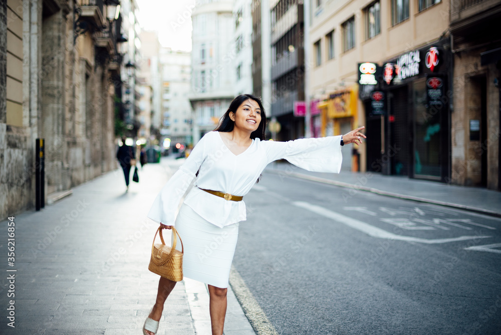 Fototapeta premium pretty young latin woman calling a taxi in the city