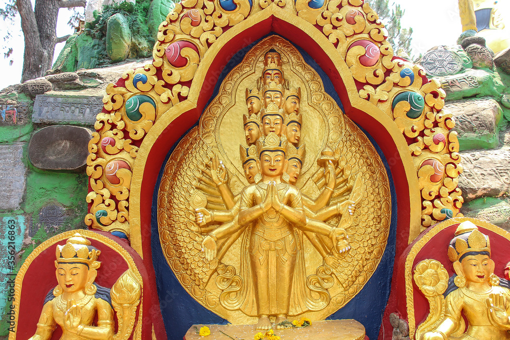 View of carved golden statue of eleven-headed Avalokiteśvara bodhisattva who embodies the compassion of all Buddhas. Monument is located in Buddha Garden in Kathmandu city, Nepal.