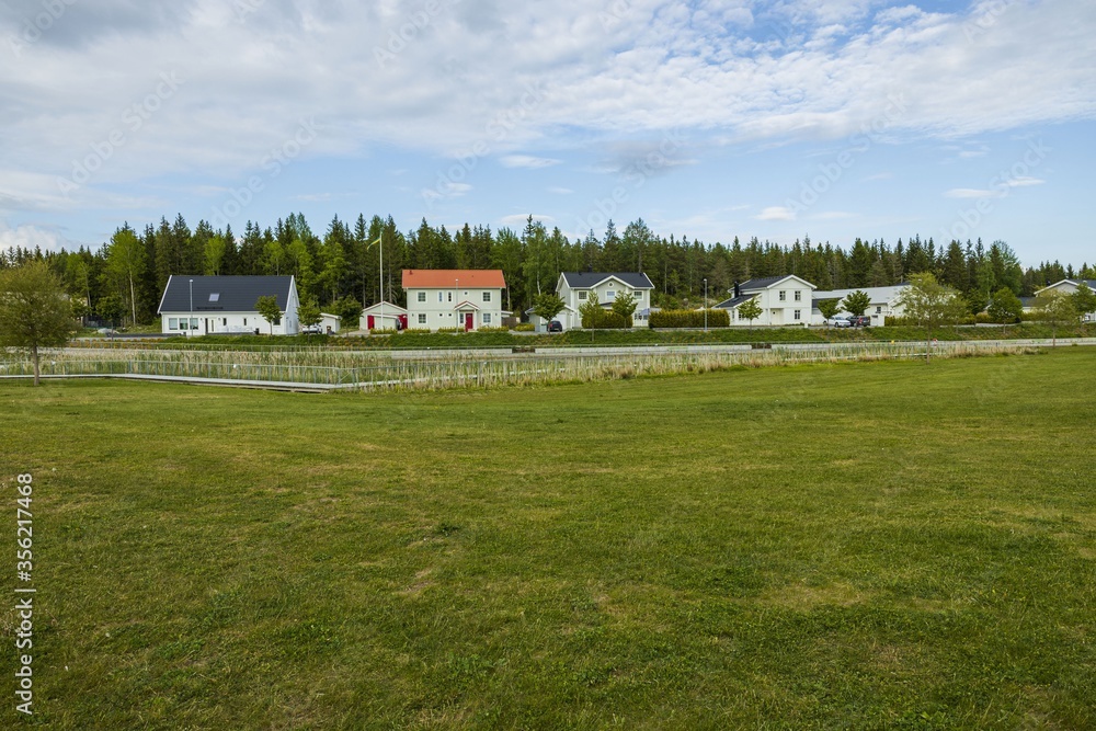 Beautiful landscape view of group of private houses on green forest trees and blue sky with white clouds background. Europe. Sweden. Beautiful landscape view of group of private houses on green forest trees and blue sky with white clouds background. Europe. Sweden.