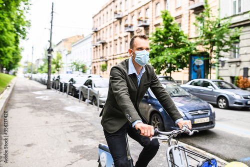 A guy in a medical mask chooses to ride a bicycle to get at the office to avoid crowding in public transport during a pandemic, an epidemic