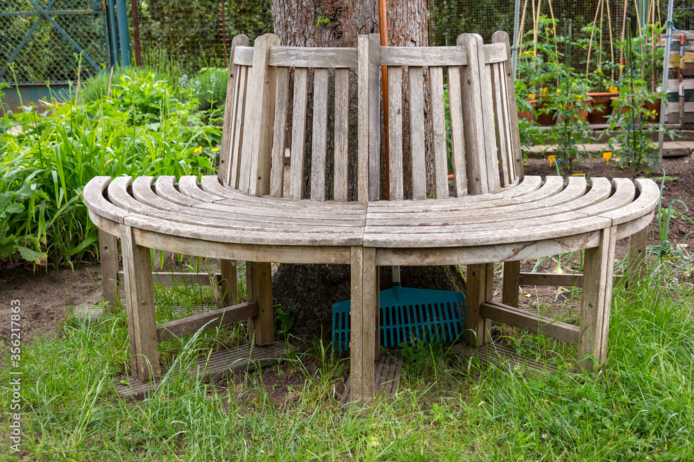 View of a wooden round bench in an allotment garden.