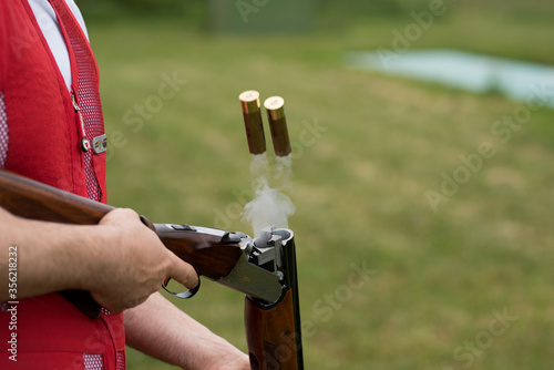 Rifle cartridges and smoke after firing. Man opens the shotgun bolt after  shot with smoke